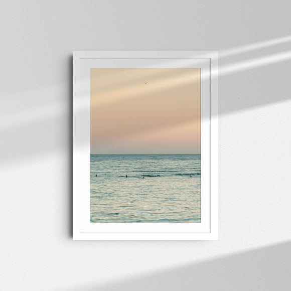 A framed fine art photography print featuring surfers on the green ocean at sunset in Malibu, California.