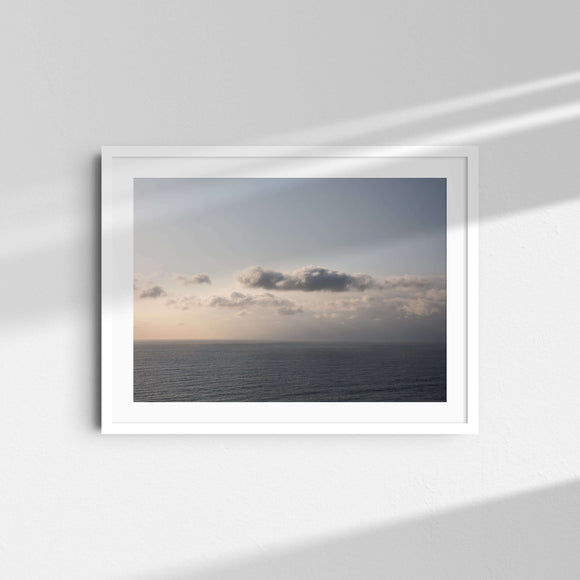 A framed fine art photography print featuring stormy clouds in the sky hanging over the ocean.
