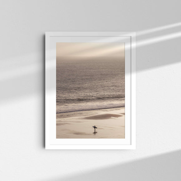 A framed fine art photography print featuring a single surfer on the sand and a sunset over the ocean in Malibu, California.