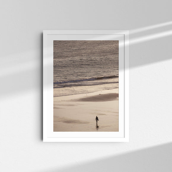 A framed fine art photography print featuring a single surfer on the sand and a sunset over the ocean in Malibu, California.
