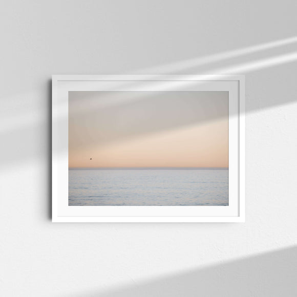 A framed fine art photography print featuring a soft blue and yellow pastel sunset over the ocean.