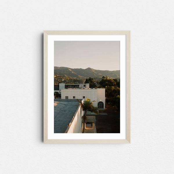 A framed fine art photography print featuring the downtown Santa Barbara city with mountains in the background at sunrise.