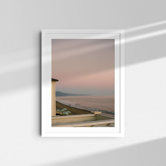 A framed fine art photography print featuring the pink and purple sunset over the ocean and people walking in Santa Barbara, California.