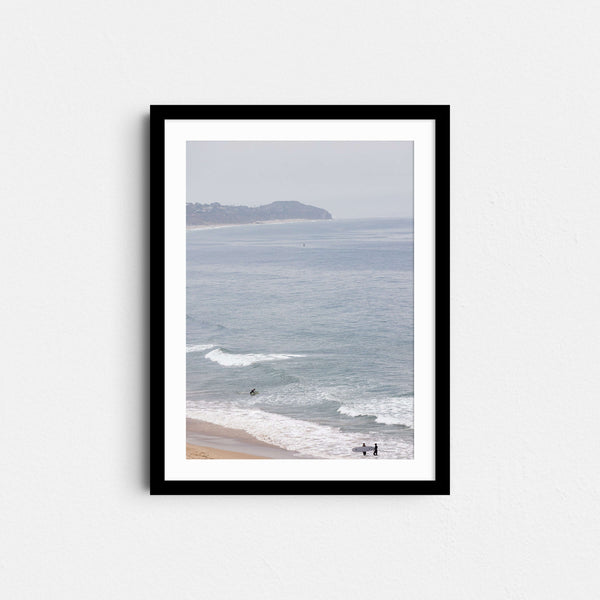 A framed fine art photography print featuring a single surfer in light blue ocean waters in Malibu, California.